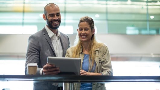 smiling-couple-using-digital-tablet-waiting-area_107420-95826